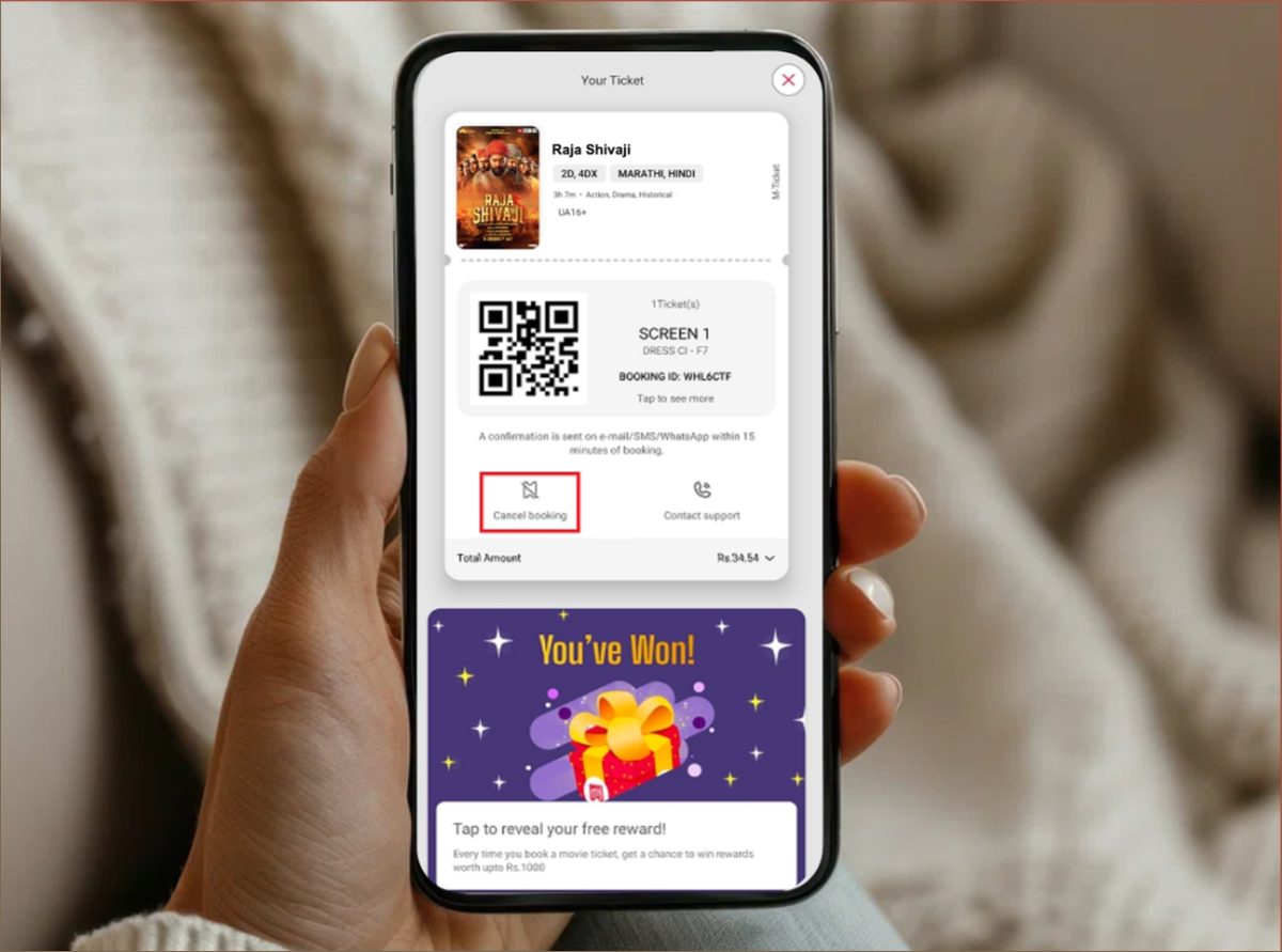 A confirmed BookMyShow ticket on a phone, showing the QR code and booking ID